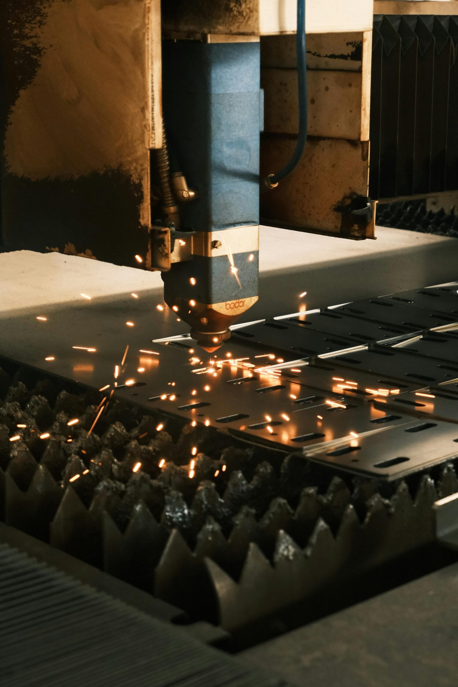 Close-up of a laser cutter in action, producing sparks in a modern manufacturing facility.